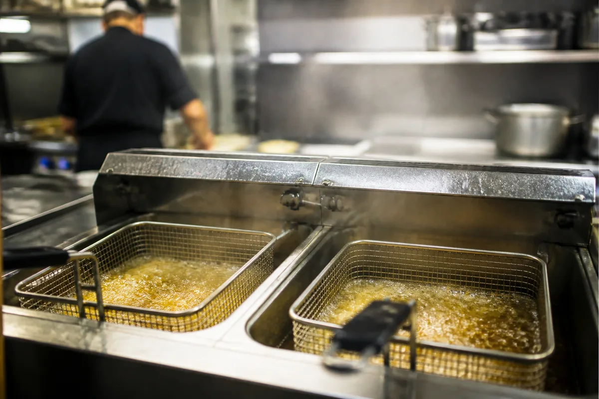 Friteuse professionnelle en fonctionnement avec deux paniers séparés dans une cuisine rapide